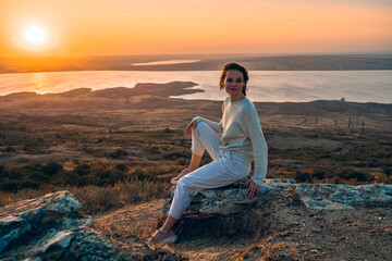 beautiful girl on a rock in the sunset background.