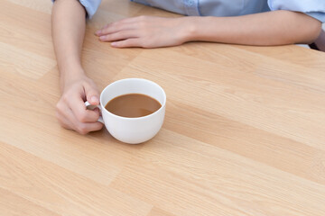 Coffee latte in holding hand business woman on wooden desk.