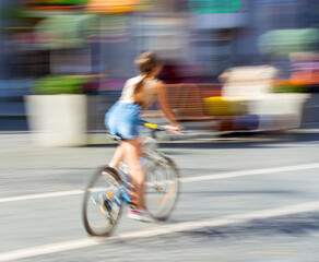 Woman on bicycle in motion riding down the street