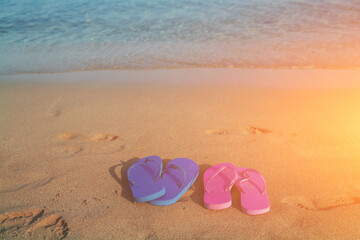 Fototapeta na wymiar Romantic beach scene. Female and male flip flop sandals on the beach at sunrise