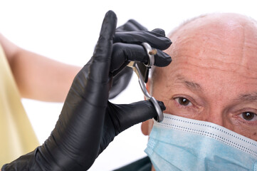 Closeup image of senior man in protective face mask  in barber shop.Barber cutting hair with...