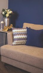 Living room interior with blue walls, soft, cozy sofa with pillows. Flowers, white roses in a vase.