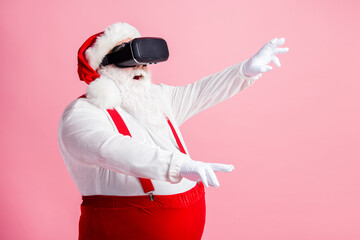 Fototapeta na wymiar Profile side view portrait of his he nice attractive bearded fat overweight Santa watching vr wear futuristic innovation helmet device enjoying realistic illusion isolated pink pastel color background
