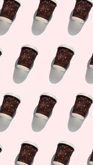 Coffee to go regular pattern with natural shadows on pink background top view. Brown paper cups lids for take away hot drinks in cafe shop. Lifestyle concept flat lay vertical desktop 9:16 wallpaper.