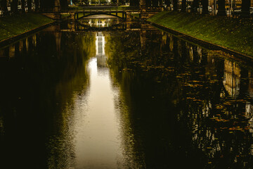 Autumn city canal with fallen leaves and reflections