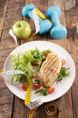 diet food concept-grilled chicken, dumbbell and meter
