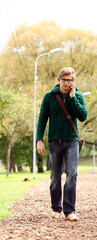 Handsome guy walking with cellphone in park