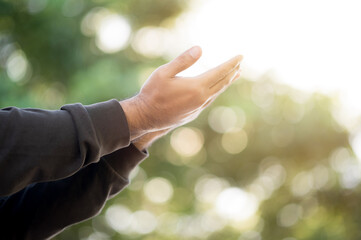 Praying male hands for hope stretch into the sky on nature background with sun light. Religion and belief concept.