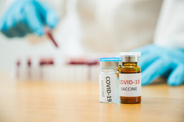 Close up medicine liquid vaccine vial bottle and Blood test samples of coronavirus. COVID-19 concept.