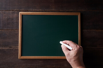 hand holding chalk on mini blackboard