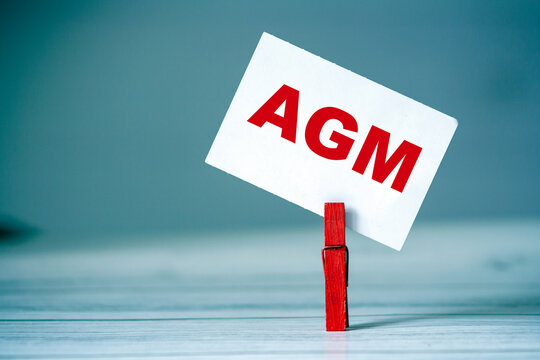 Reminder sticky note with clothes pin on table. Sticky note with word AGM. Business strategy