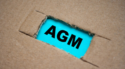 A cut-out hole in the paper cardboard, and under it a piece of paper with the word AGM. The word AGM