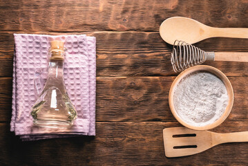 Flour in the bowl, spatula oil bottle and towel on the kitchen table background.