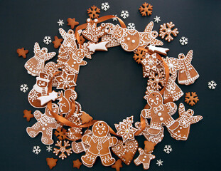 Christmas wreath made from gingerbread cookies with icing and confectionery mastic snowflakes on black background with space for text. Holiday food, homemade baking, Christmas and New Year traditions. - 383776477