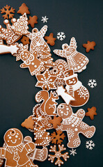Christmas gingerbread cookies with icing and confectionery mastic snowflakes on black background, view from above. Holiday food, homemade baking, Christmas and New Year traditions.