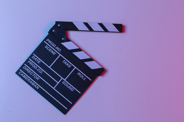 Naklejka premium Film clapper board in blue red neon light. Cinema industry, entertainment