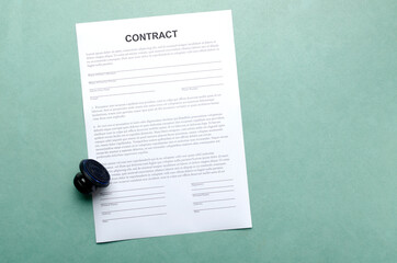 Top view of contract document and stamp on the blue desk