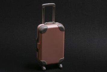 Travel or trip concept. Mini plastic travel suitcase on black background. Minimal style