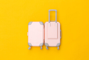 Travel concept. Mini plastic travel suitcase on yellow background. Minimal style. Top view, flat lay