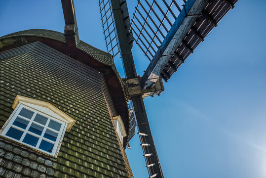 Old, wooden mill tower closeup with a small window and blades conveys rural, ancient industrial concept. Old windmill blades represent a past technology used for food grinding and production