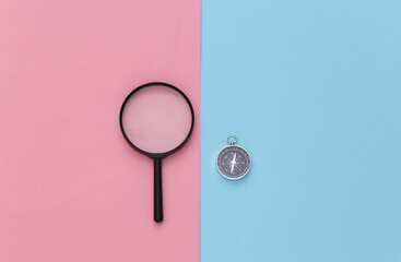 Minimalism travel, adventure flat lay. Compass and magnifier on a blue-pink pastel background. Top...