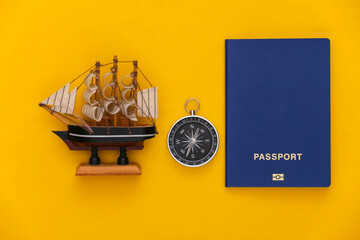 Minimalism travel, adventure flat lay. Compass and ship, passport on yellow background. Top view