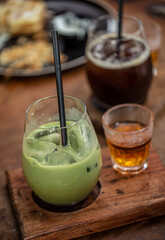 Green Matcha Latte and coffee in the glass cup served with hot tea on wooden board