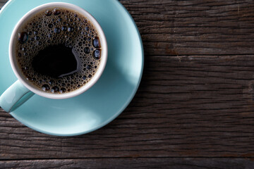 Coffee cup with black coffee on wooden table, top view