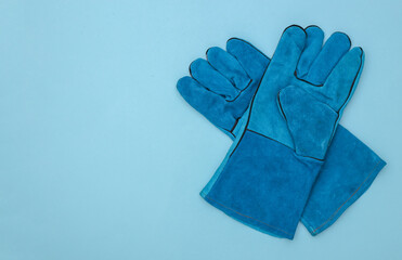 Work gloves on a blue background with copy space. Top view
