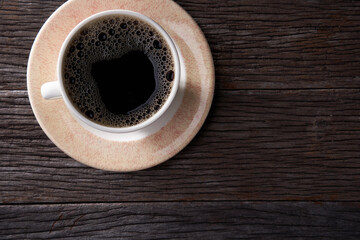 Coffee cup with black coffee on wooden table, top view