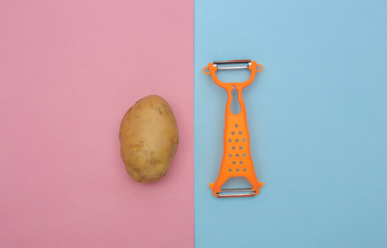 Knife for peeling skin and potato on blue pibk background. Top view