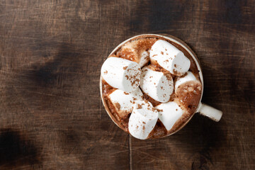 Hot cocoa or hot chocolate with marshmallows in a ceramic Cup on a brown wooden table	