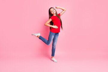 Full body size photo of lovely sweet small lady long hairstyle show v-sign dance raise leg hand hip toothy smile wear casual red t-shirt jeans sneakers isolated pink color background