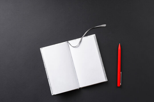 notebook with red pen on black background