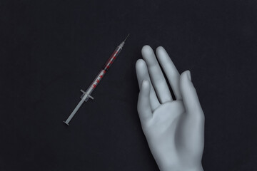 White hand mannequin and syringe on black background. Drug addiction