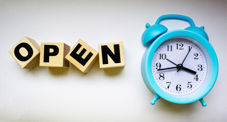Open, text on wooden cubes, next to alarm clock on white background