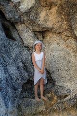 Cute little girl standing between the rocks. Caucasian girl wearing dress and hat. Happy childhood. Summer concept. Traveling with kid. Bali, Indonesia