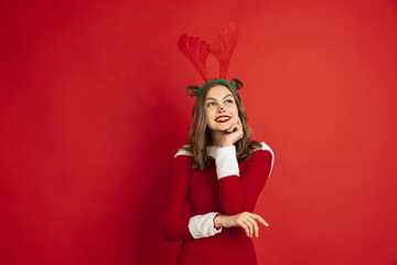 Dreamful. Greetingcard. Concept of Christmas, 2021 New Year's, winter mood, holidays. Copyspace for ad, postcard. Beautiful caucasian woman with long hair like Santa's Reindeer catching giftbox.