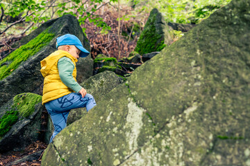 Little boy adventure hiking and climbing in mountains
