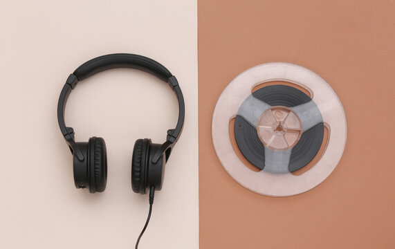Stereo headphones and magnetic audio reel on brown beige background. Top view