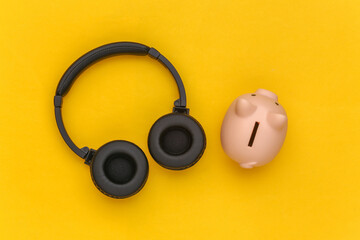 Piggy bank and stereo headphones on brown beige background. Top view