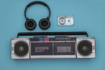 Boombox audio tape recorder, stereo headphones and audio cassette on a blue background. Retro 80s. Top view. Flat lay
