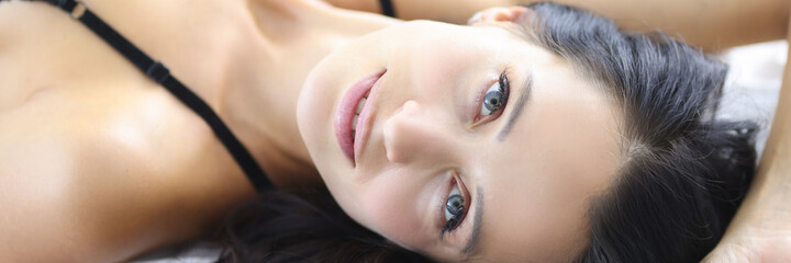 Portrait of a brunette woman lies on bed in a bra. Sexy woman concept