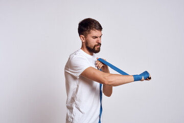 sports man in white t-shirt blue boxing bandages on his arms workout exercises