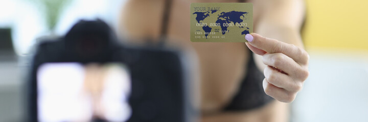 Woman in lingerie holds out bank card to camera. Safe internet payments concept