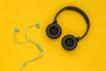 Wireless Stereo headphones and wired earphones on yellow background. Top view. Flat lay