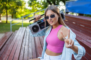 Fashionable stylish blonde caucasian woman in sunglasses dressed in youth summer clothes holding a...
