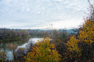 Autumn morning in rainy day with river and forest on the shores. Autumn landscape.
