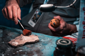 Close up macro shot of expert forensic officer during a delicate operation on a fossil. Preparing and dusting for prints after DNA extraction from crime scene evidence.