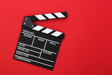 Fototapeta na wymiar Film clapper board on red background. Cinema industry, entertainment. Top view